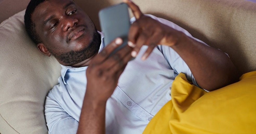 Man laying in bed looking at his cellphone.