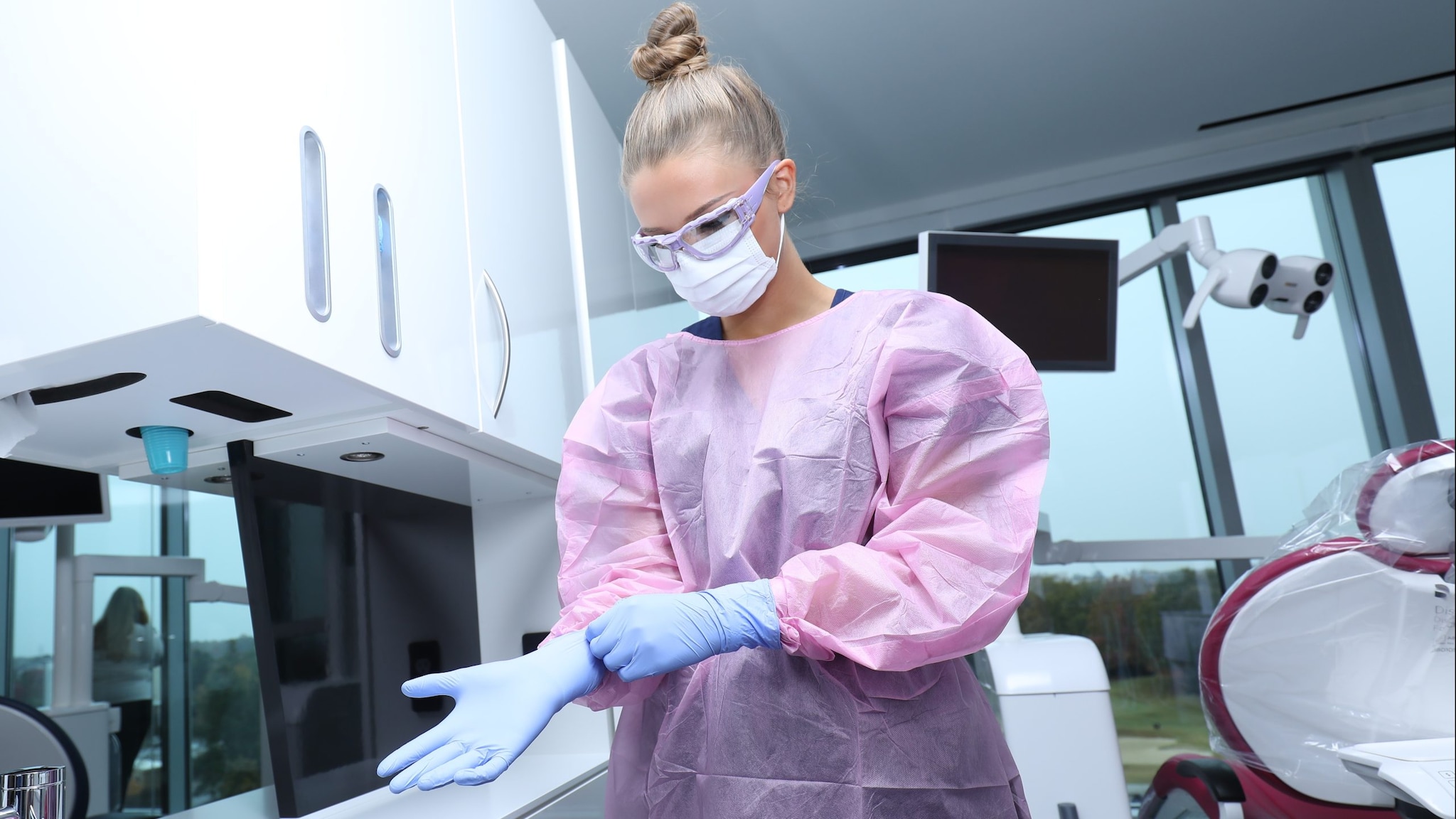 Dental health care personnel donning gloves.
