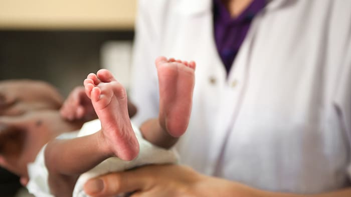Healthcare provider holding a small newborn.