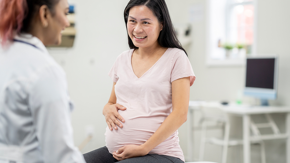 A pregnant woman sitting in a doctor's office speaking to her doctor