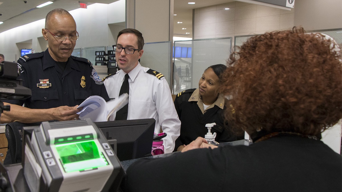 Customs and Border Protection Officer works with two CDC Quarantine Public Health Officers to assess a sick traveler