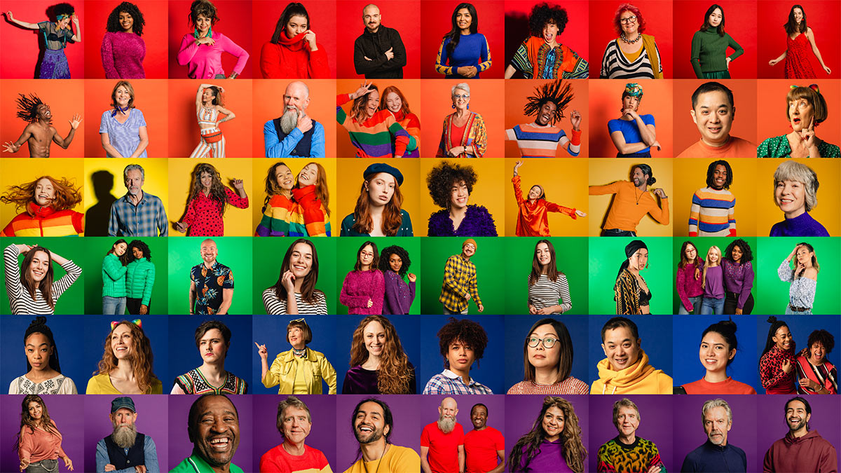 Persons on a brightly colored background arranged to represent the LGBTQ+ flag.